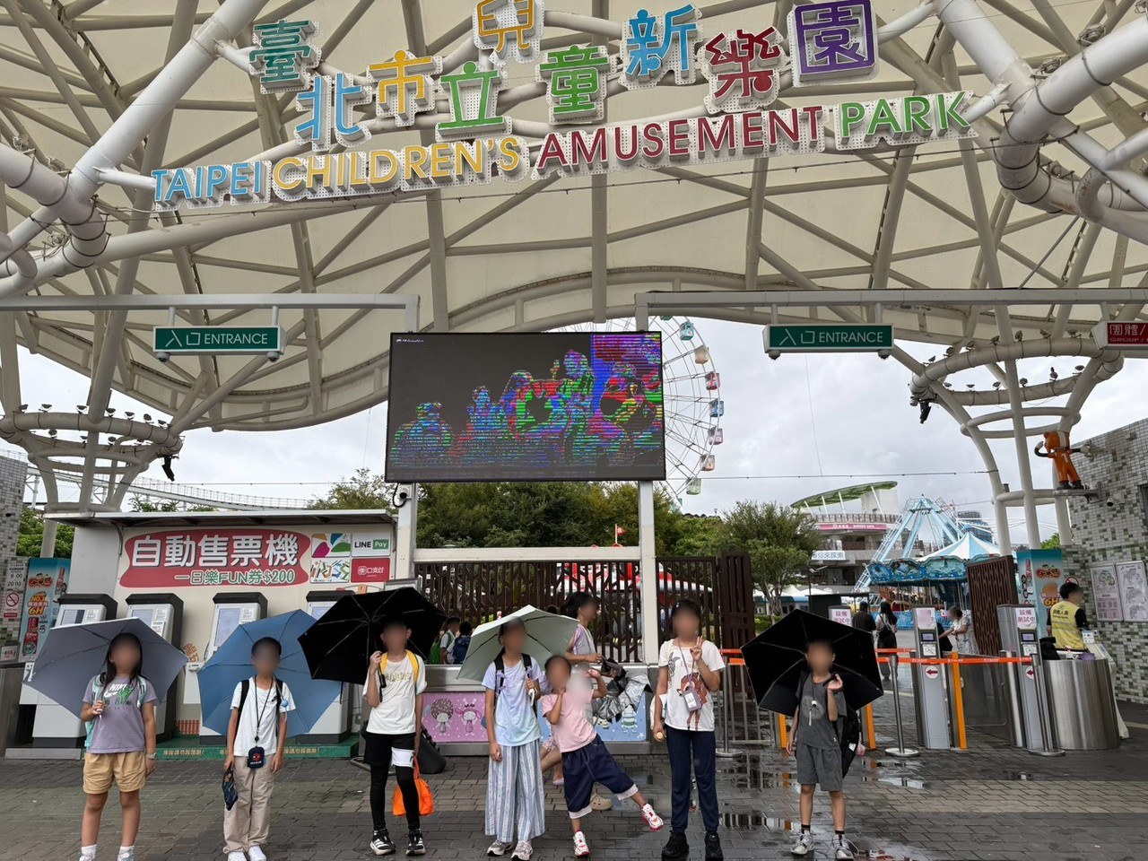 學生在臺北市立兒童新樂園入口撐傘合影